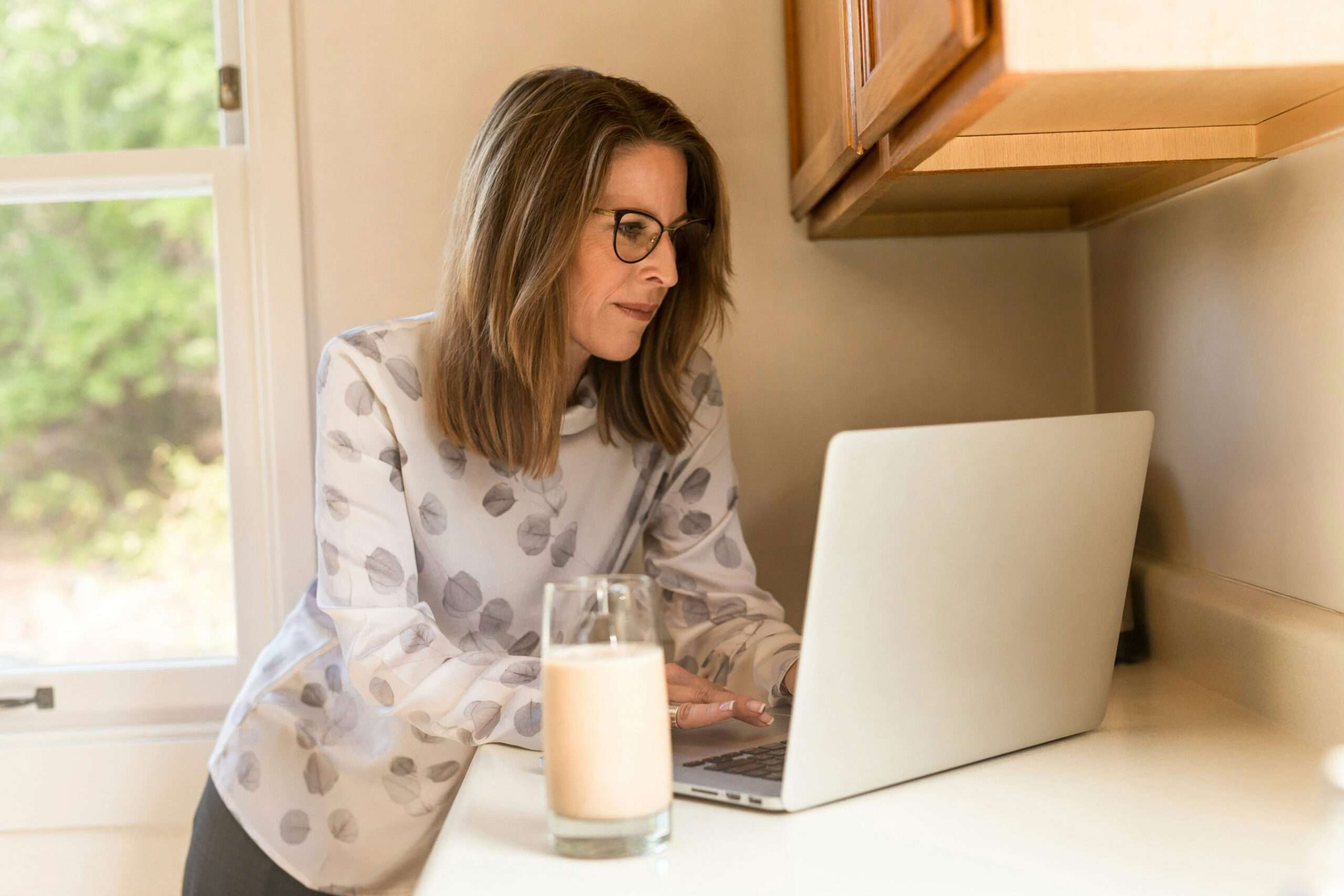 Older woman using a laptop at home, seeking support for menopause-related body image and eating concerns to improve her quality of life.